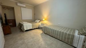 a bedroom with two beds and a lamp on a tiled floor at Casa Piedra Roja in Villa Unión