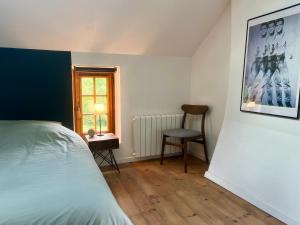a bedroom with a bed and a chair and a window at Charmante maison de campagne proche village in Bonnebosq
