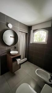 Un baño con lavabo, inodoro y ventana. en Arístides Lodge, en Mendoza
