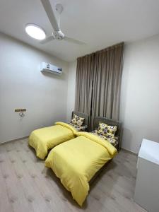 two beds in a room with yellow sheets at شقق مفروشة صلالة - Furnished Apartments Salalah in Salalah