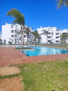 a swimming pool with a palm tree in front of a building at Bajo con barbacoa Solymar LAS TERRAZAS GOLF RESORT in Torre-Pacheco