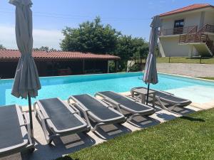 a group of lounge chairs and umbrellas next to a swimming pool at Kasa da Caniçada - Gerês in Braga