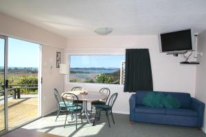 a living room with a table and chairs and a tv at Cook's Lookout Motel in Paihia