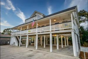 une grande maison avec des colonnes blanches et un drapeau dans l'établissement Beach Haven 4 bed 3 ba - Lower Unit, à Tybee Island
