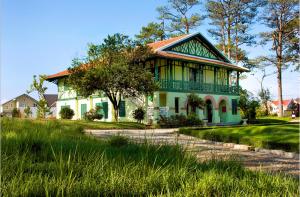 a green and white house with a tree at Dalat Cadasa Resort in Da Lat