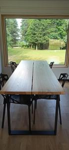 a wooden table in front of a large window at Dom w lesie in Przytuły
