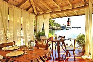 a porch with tables and chairs and a view of the water at Villa Camilla 10 Pax by VILLASRETREATS in Sarzana