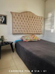 a bedroom with a large bed with a large headboard at A 5 minutos del aeropuerto in Bogotá