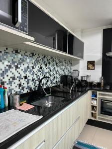 a kitchen with a sink and a microwave at Suíte Conforto com AR, TV e sacada em Florianópolis in Florianópolis