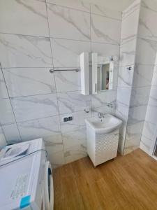 Un baño blanco con lavabo y espejo. en First Line Apartment, en Balchik 24 fotos más