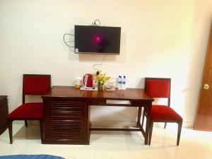 a wooden table with two red chairs and a television on a wall at AN THINH Hotel & Homestay in Bình Tú +26 photos