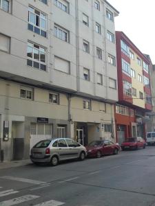 two cars parked in front of a tall building at Hostal Fisterra in Lugo