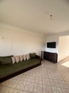 a living room with a green couch and a flat screen tv at Vue sur mer in El Harhoura