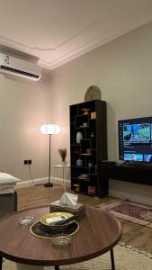 ein Wohnzimmer mit Tisch und Fernseher in der Unterkunft ستديو in Riad