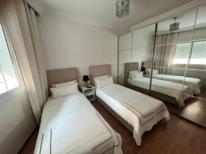 une chambre avec deux lits et un miroir dans l'établissement Apartamento, à Tanger