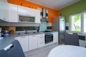 a kitchen with white cabinets and an orange and green wall at Seaside holiday house Zubovici, Pag - 22859 in Zubovići