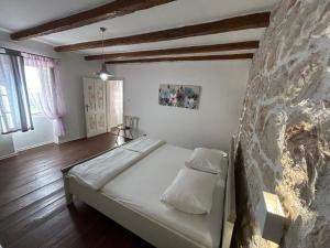 Bett in einem Zimmer mit einer Steinmauer in der Unterkunft Family friendly house with a swimming pool Mundanije, Rab - 23393 in Rab