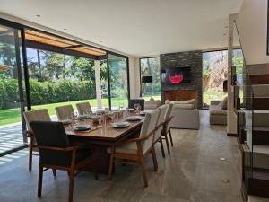 a dining room with a table and chairs and a fireplace at Villa en el Bosque de Avándaro - Vista al Lago in Valle de Bravo