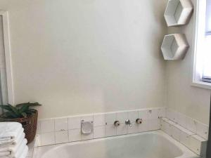 a white bath tub in a bathroom with a plant at D118 Cawood Family Stay in Sunshine +35 photos