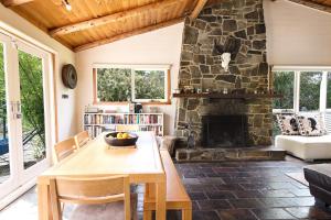 a living room with a table and a stone fireplace at Coastal Cottage Bicheno in Bicheno