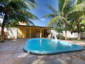 a swimming pool in front of a house with palm trees at Aconchego da Nina in Jijoca de Jericoacoara