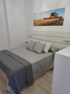 Un dormitorio con una cama con un cuadro en la pared. en Apartamentos ESPIGAS PUERTO, en Valencia