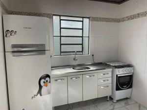 a small kitchen with a penguin on the refrigerator at J Morelli s - A 2 Minutos dos Melhores Parques de Olímpia in Olímpia +36 photos