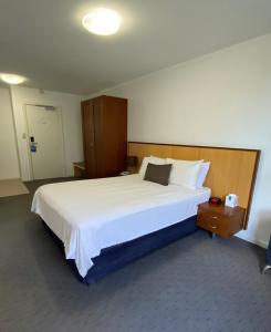 パースにあるOcean Beach Hotelのベッドルーム(白い大型ベッド1台、木製ヘッドボード付)