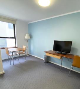 パースにあるOcean Beach Hotelのデスク、テレビ、テーブル、椅子が備わる客室です。