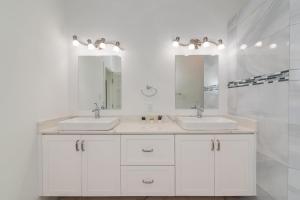 a white bathroom with two sinks and two mirrors at Luxurious 4 Bedroom Home on Seven Mile Corridor in the Heart of Cayman with a Private Pool in Seven Mile Beach +7 photos