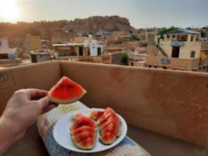 a person holding a slice of watermelon on a plate at Hotel Janat Heritage in Jaisalmer