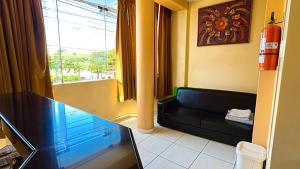 a living room with a black couch and a window at Hospedaje Sol de Oro in Nazca