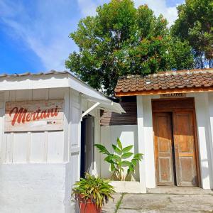 a small white building with a door and a tree at Mertanihuisjogja in Salakan +7 photos