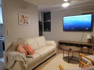 a living room with a white couch and a flat screen tv at Spacious Apartment Oasis in Bankstown