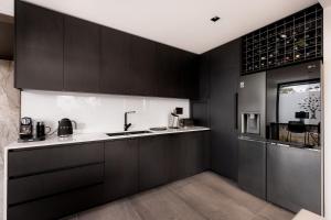 a kitchen with black cabinets and a sink at Luxe Hobart Villa - Boxwood in Hobart