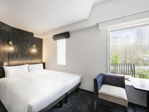 東京にある東急ステイ西新宿のベッドと机と窓のある寝室