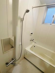 un bagno bianco con doccia e vasca di SUITE YONEGAHAMA l 米が浜通 a Yokosuka