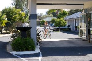 una mujer montando una bicicleta por una calle en Gale Street Motel & Villas en Busselton