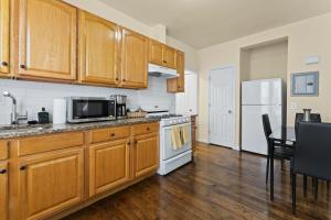 a kitchen with wooden cabinets and a white refrigerator at The Commuter Dream Apartment close to NYC in Newark
