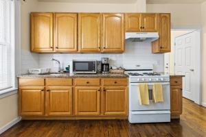 a kitchen with wooden cabinets and a white stove top oven at The Commuter Dream Apartment close to NYC in Newark +2 photos