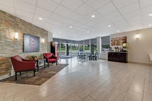 a lobby with red chairs and tables and a brick wall at Red Roof Inn & Suites Wilkesboro in Wilkesboro