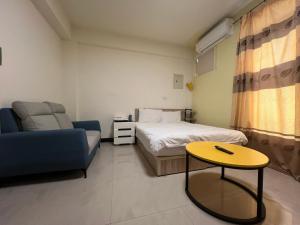 ein Zimmer mit einem Bett, einer Couch und einem Tisch in der Unterkunft 市區背包客棧-有套房及包棟 in Jincheng
