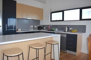 a kitchen with a counter and two stools in it at Selbourne by the Sea in Scamander in Scamander