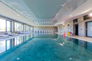 a swimming pool with chairs and a swimming pool at Lotos Spa by Major Domus Club in Dziwnów