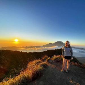 a woman standing on top of a mountain at sunset at Mount Batur Sunrise and Sunset Camping in Bangli