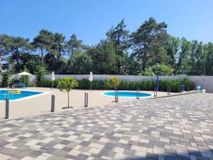 a courtyard with two pools with umbrellas and trees at Aphrodite Olimp - Luxury apartment with sea view & pool in Olimp
