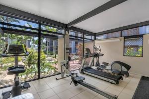 a gym with treadmills and ellipticals in a room with windows at Tropic Nest - A Relaxed Resort Escape for Couples in Cairns
