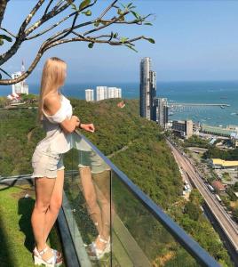 Una mujer parada en lo alto de una torre mirando la ciudad. en Sea View Spacious Condo Near Walking Street, en Pattaya South