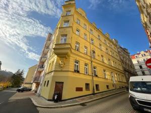 a yellow building with a clock tower on a street at Francis Apartment II - Spa Center Karlovy Vary in Karlovy Vary