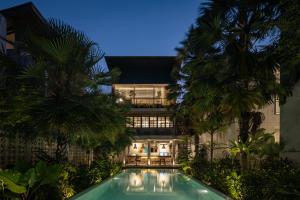 an exterior view of a building with a swimming pool and palm trees at T Lofts in Seminyak